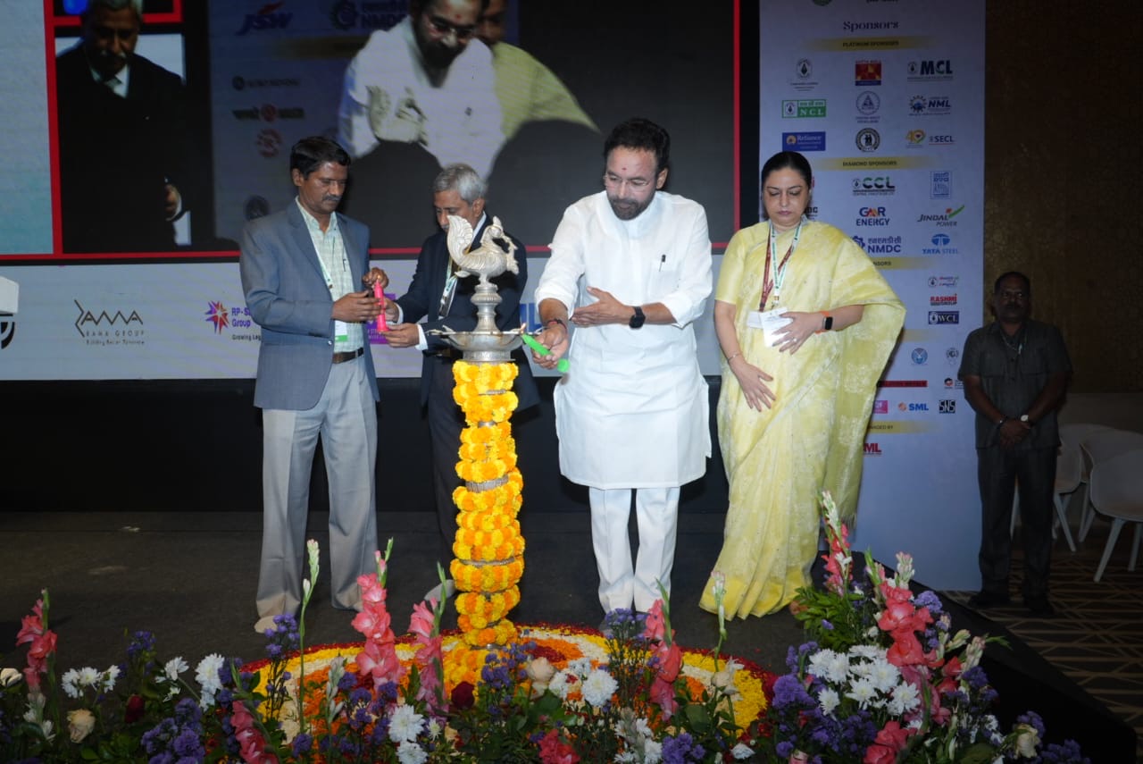 G. Kishan Reddy lighting a tall ceremonial brass lamp decorated with marigolds at the opening of a conference, alongside other dignitaries