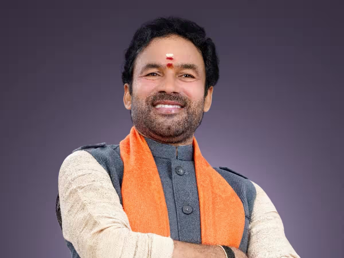 Portrait of G. Kishan Reddy smiling, arms folded, wearing a cream kurta, grey waistcoat and a saffron stole