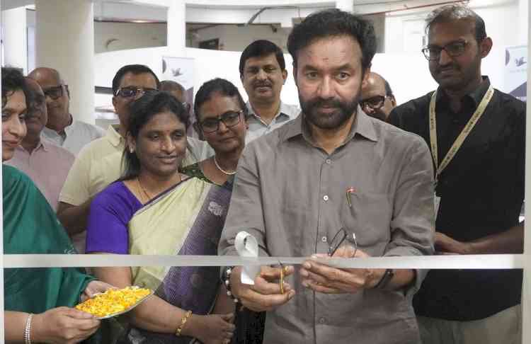 G. Kishan Reddy cutting a white ribbon with scissors to open a facility, with women and men in formal and traditional dress watching, one holding a plate of turmeric rice