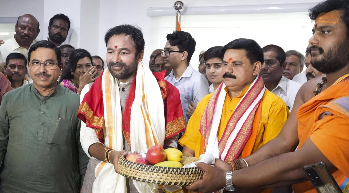 G. Kishan Reddy in a red shawl receiving a basket of fruit from priests, with colleagues and officials around him