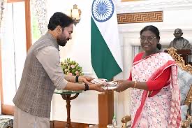 G. Kishan Reddy presenting a document to a woman seated in a red sari during a formal call, with the Indian flag and a bust in the background