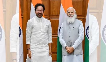 G. Kishan Reddy in a white kurta standing beside a senior leader in a grey waistcoat, with Indian flags behind them in a wood-panelled room
